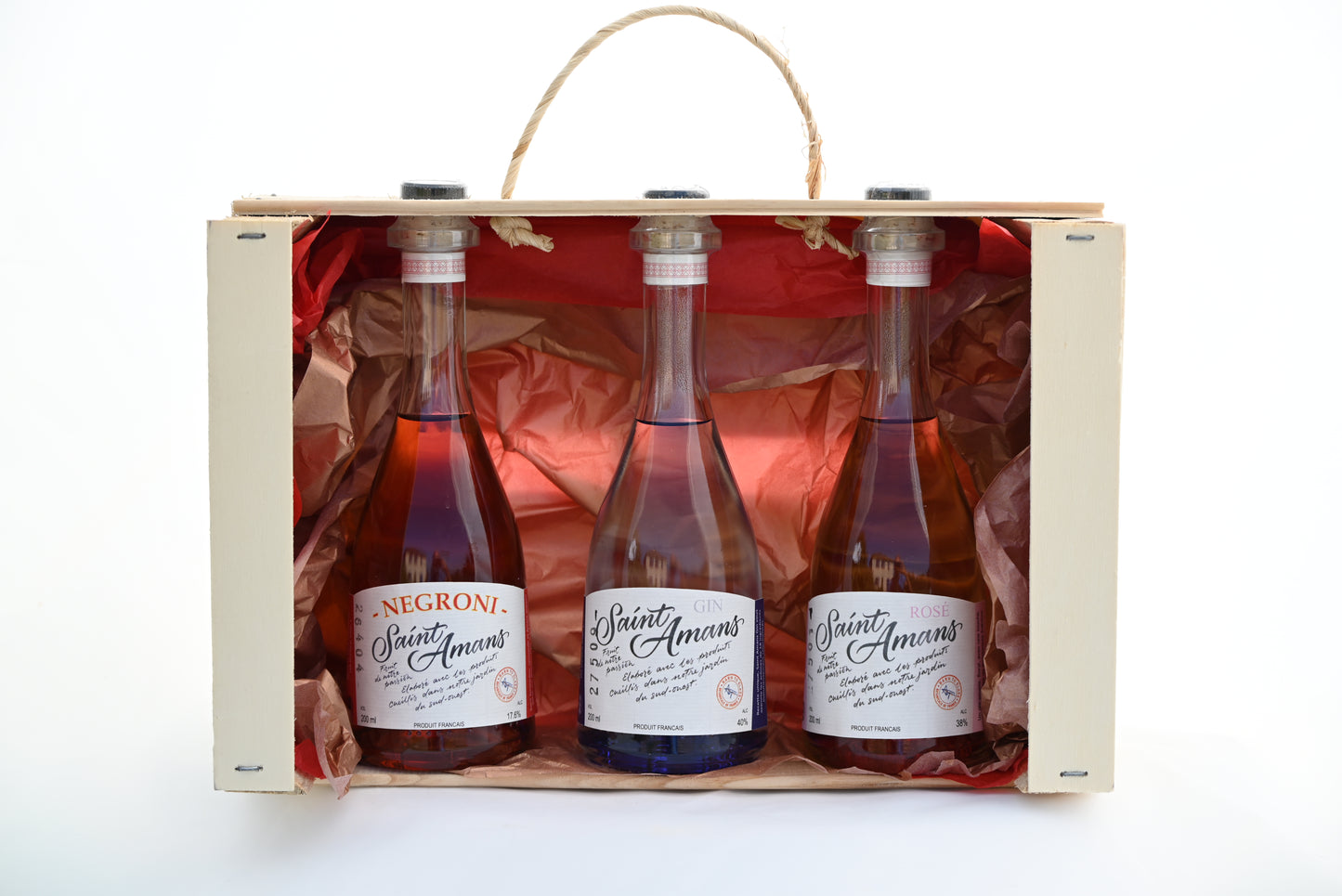 Our gorgeous trio gift set: 3 20cl bottles: our 40° Saint Amans Original gin, 38° Rosé Gin and 17,6° ready-to-drink Negroni by Saint Amans in a case with red paper in the back. French: Notre splendide coffret-cadeau trio : 3 bouteilles de 20 cl : notre Gin Original Saint Amans de 400, notre Gin Rosé de 38° et notre Negreoni par Saint Amans prêt-à-boire de 17,6° dans une caisse avec du papier rouge au fond.
