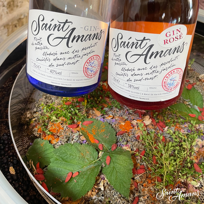 Our beautiful bottles, straight from our family barn distillery, to your door. Pictured are our Original gin and Rosé Gin surrounded by some of their key components, such as mint and carmine. French: Nos sublimes bouteilles, tout droit sorties de notre grange-distillerie familiale, prêtes à être livrées chez vous. On voir sur la photo notre Gin Original et Gin Rosé entourés de certains de leurs composants clés, comme la menthe et le carmin.