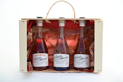 Our gorgeous trio gift set: 3 20cl bottles: our 40° Saint Amans Original gin, 38° Rosé Gin and 17,6° ready-to-drink Negroni by Saint Amans in a case with red paper in the back.  French: Notre splendide coffret-cadeau trio : 3 bouteilles de 20 cl : notre Gin Original Saint Amans de 400, notre Gin Rosé de 38° et notre Negreoni par Saint Amans prêt-à-boire de 17,6° dans une caisse avec du papier rouge au fond.