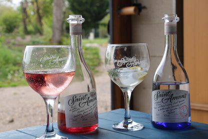 Pictured are a bottle of each of our two gins and two hand-engraved glasses, making for an elegant present. French: On peut voir une bouteille de chacun de nos deux gins ainsi que deux verres gravés à la main, un cadeau élégant.